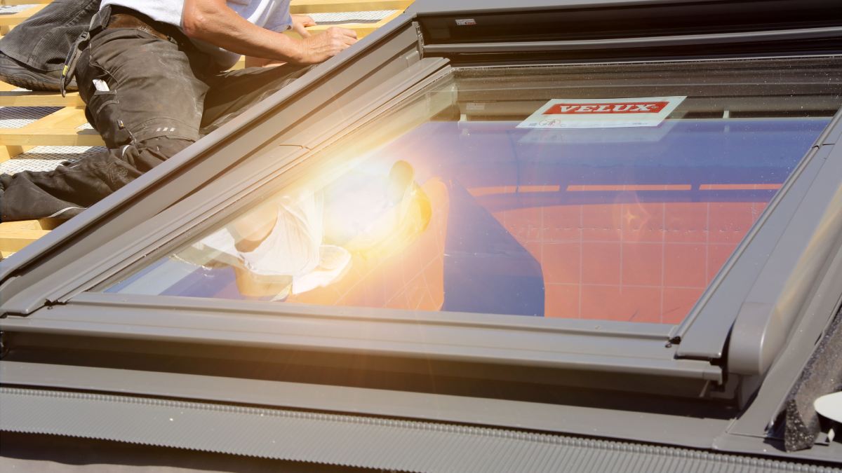Installation d'un velux sur le toit d'une habitation.