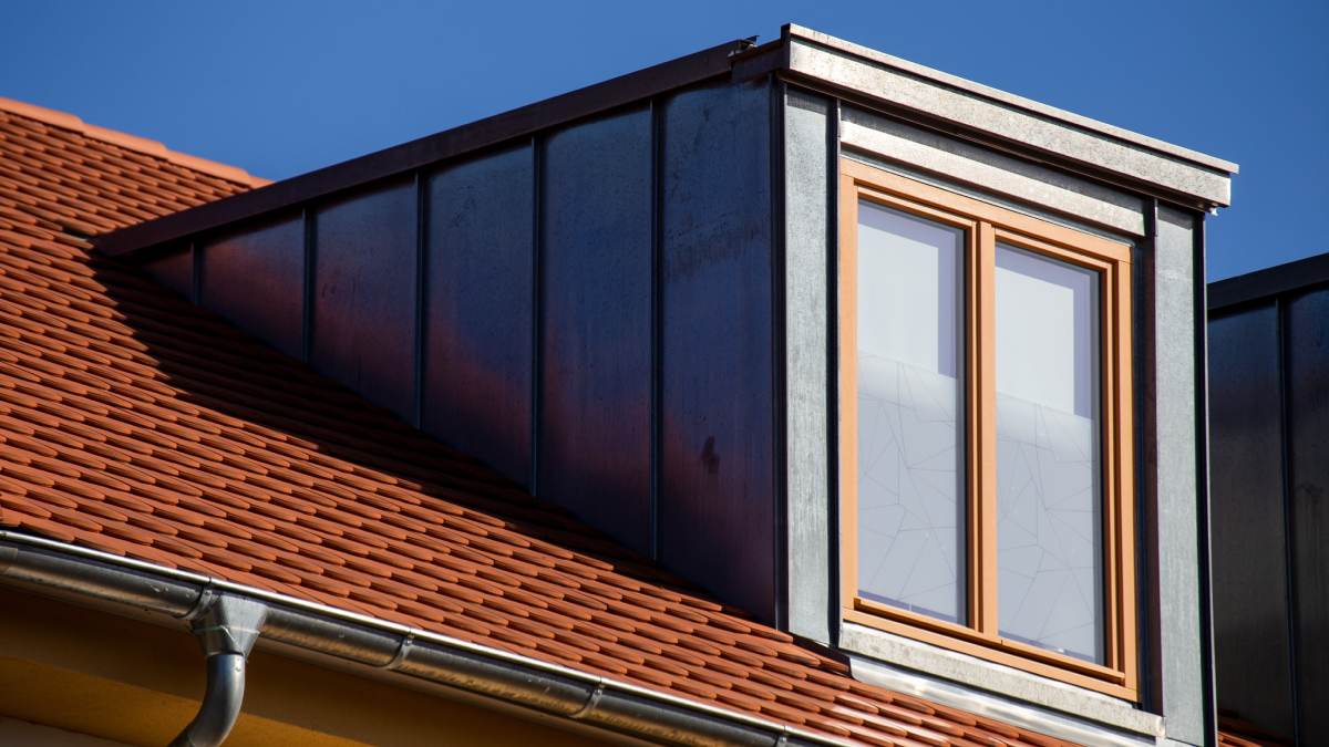 Lucarne de toit avec une toiture en tuiles de couleur orange.