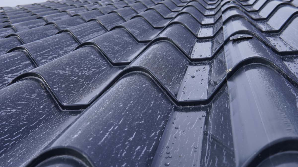 Panneaux sandwich de toiture. Installation de panneaux sandwich métalliques isolés. Vue de dessus de panneaux de toiture en métal gris anthracite avec une texture de tuile. Boulons avec rondelles EPDM.