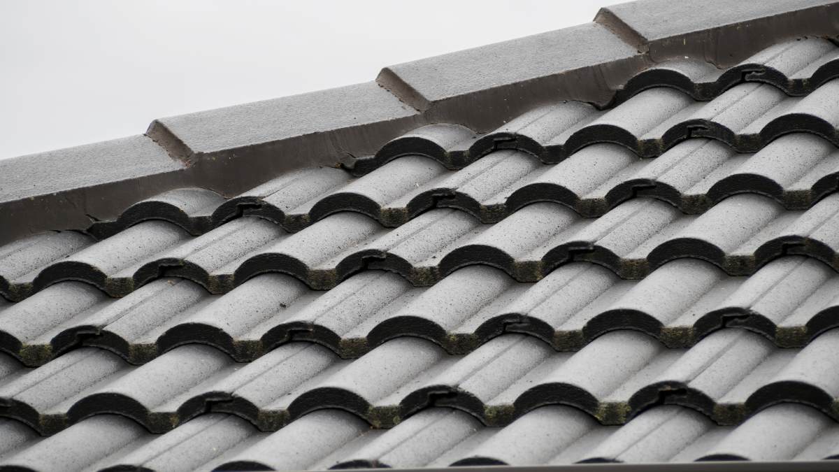 Vue en gros plan sur un toit en tuiles de béton peint en gris.