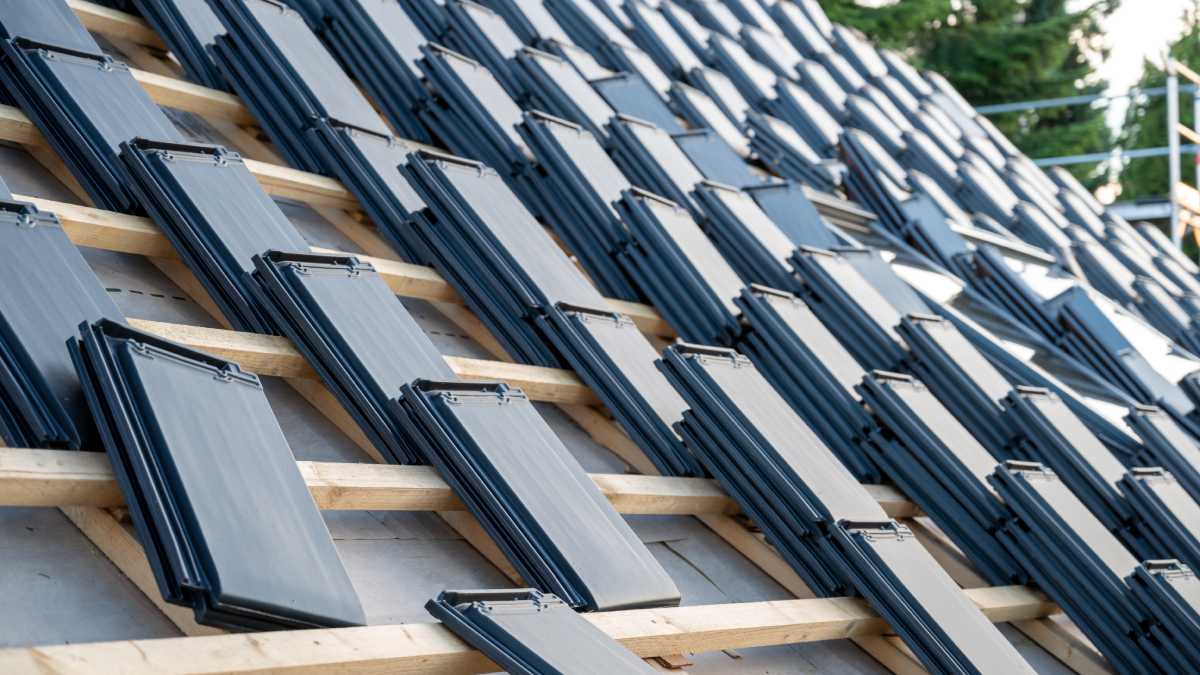 Des piles de nouveaux tuiles plates posées sur le toit d'une maison.