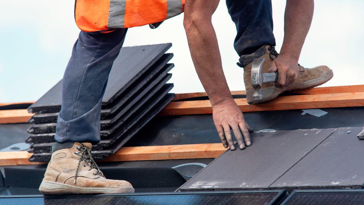 Toitures de travailleurs de la construction installant des tuiles sur le bâtiment résidentiel.