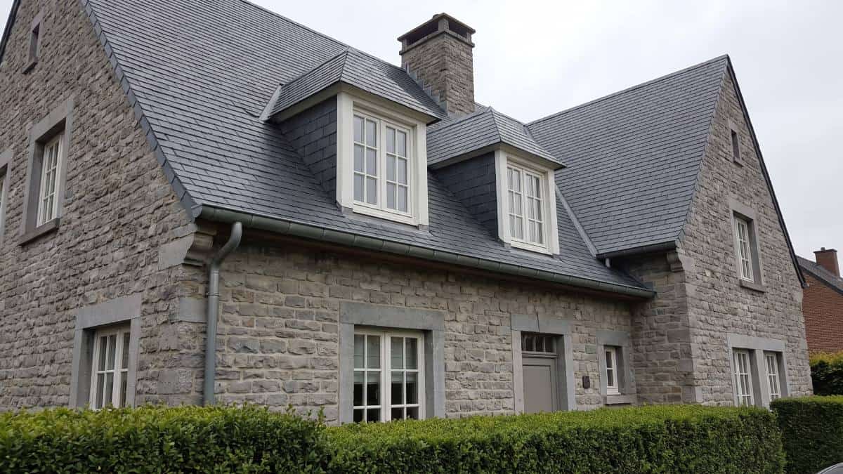 Maison en pierres avec deux chiens-assis présents sur la toiture.