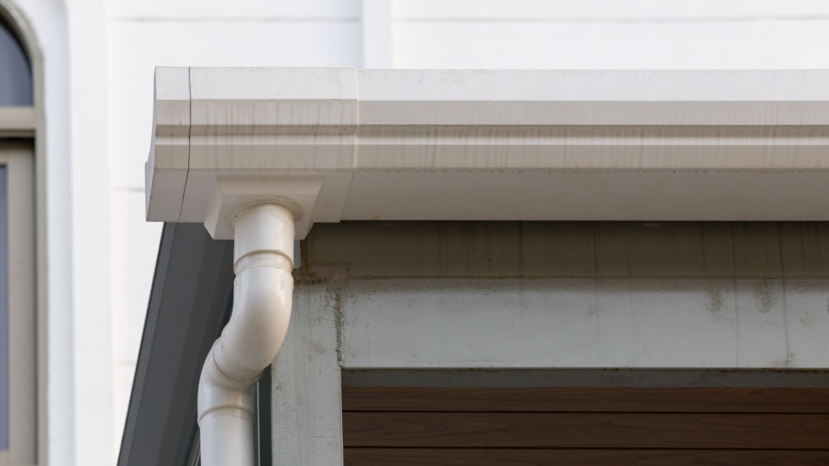 Gouttière en plastique blanc avec arrière-plan maison.