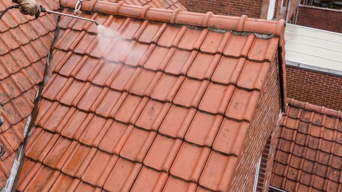 Couvreur appliquant un produit hydrofuge sur une toiture en Belgique.