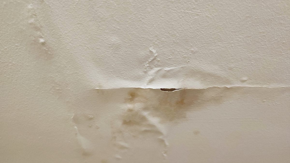 Infiltration d'eau avec humidité visible sur un mur blanc.