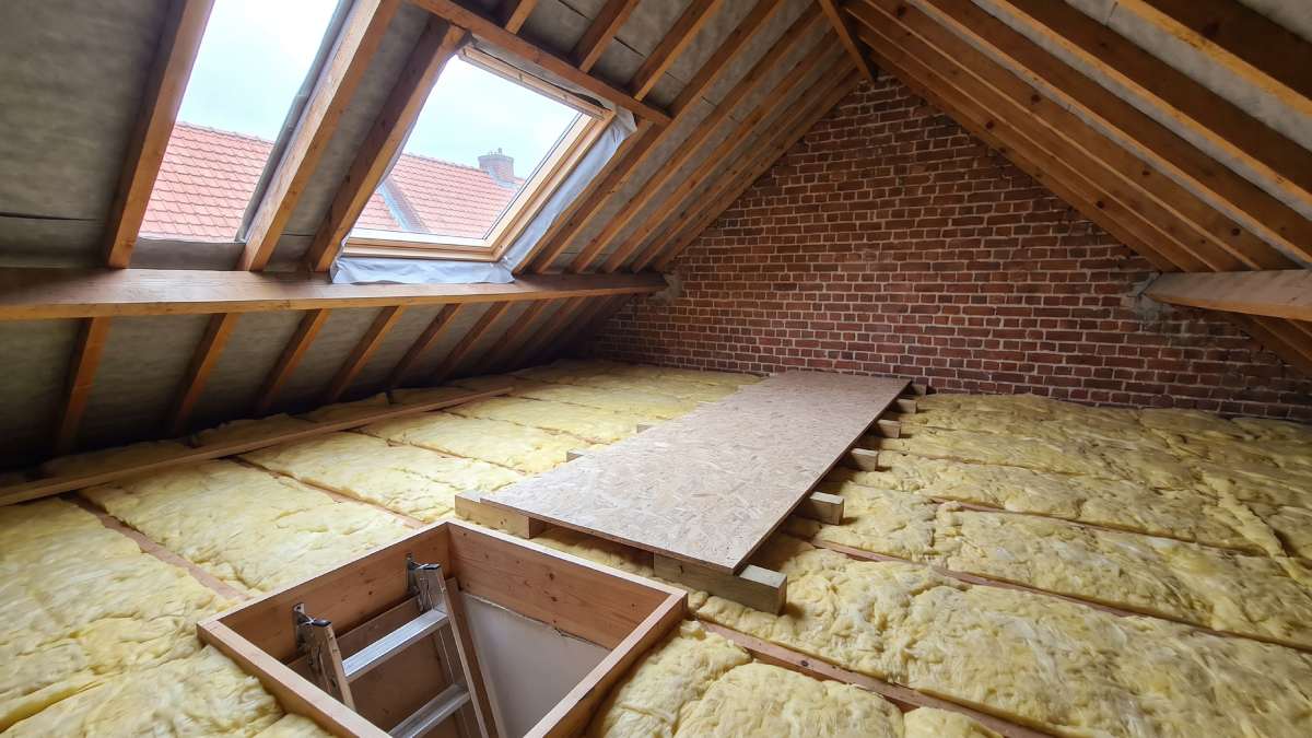 Plancher de combles correctement isolé, avec une couche épaisse et régulière et un chemin de circulation en OSB vers la trappe.