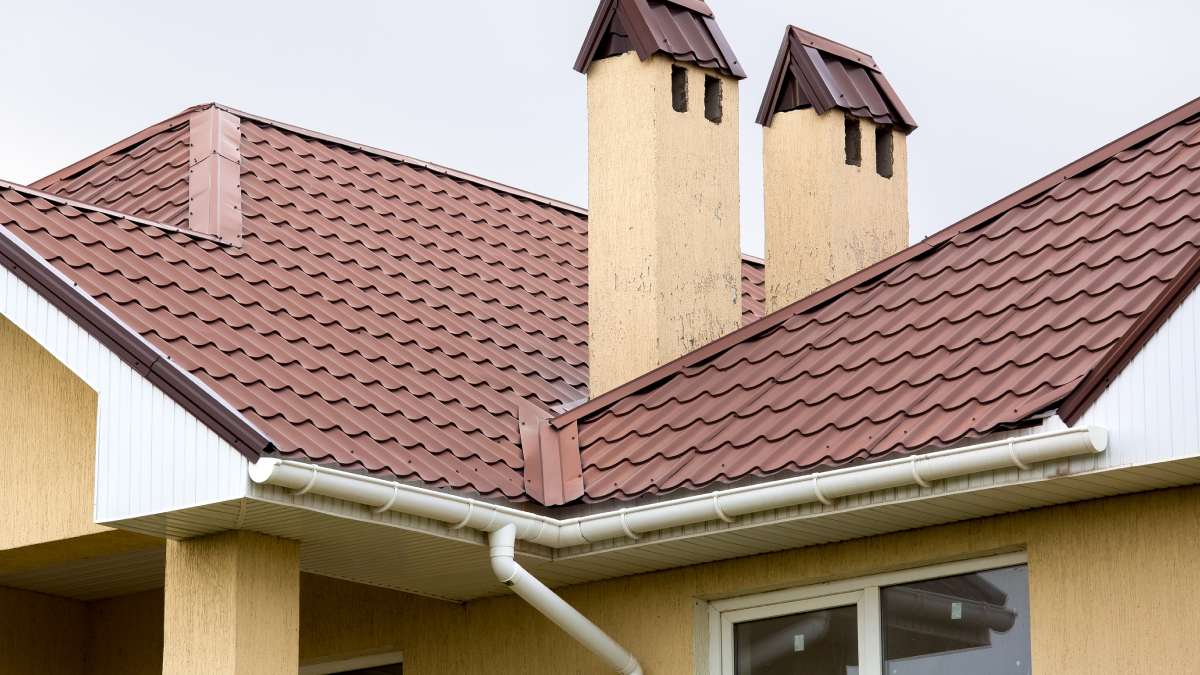 Un toit marron d'un carrelage en céramique avec un tuyau d'un système d'évacuation des eaux pluviales, gros plan sur les détails de la structure architecturale.